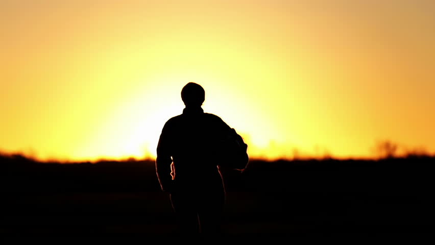Silhouette of an Air Force Pilot Walking With His Flying Helmet During Sunset at Air Base. 4K Resolution. Royalty-Free Stock Footage #1105066373
