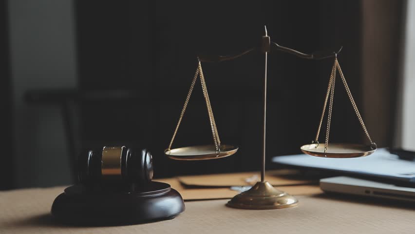 Justice and law concept.Male judge in a courtroom with the gavel, working with, computer and docking keyboard, eyeglasses, on table in morning light

