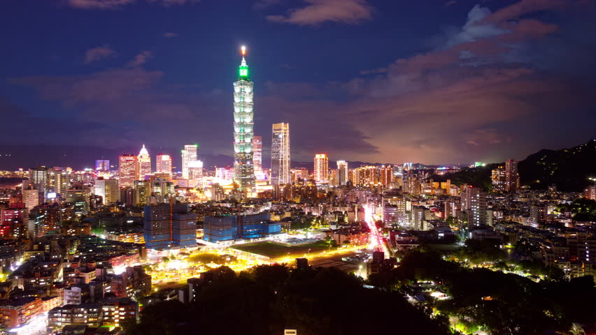 Aerial hyperlapse of Downtown Taipei at night, the vibrant capital of Taiwan, with 101 Tower standing out amid skyscrapers in XinYi Commercial District and city lights dazzling under blue twilight sky