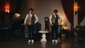 Music video, night show or event 4K. Two guys in dandy style outfit synchronically dancing in retro theatre stage. Classy male dancers performing in jazz funk style, dancing with classic cane in hands