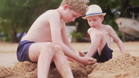 A video of two boys playing in the sand at a beach during daytime in Thailand