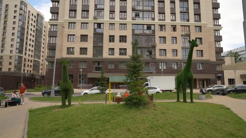 Figures of different animals are made from the lawn of bushes on a modern playground in a modern residential complex. Dolly camera