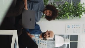 Vertical Video Startup team verify sales report with archived documents and information on laptop, comparing data to create briefing presentation. Coworkers discussing small business development