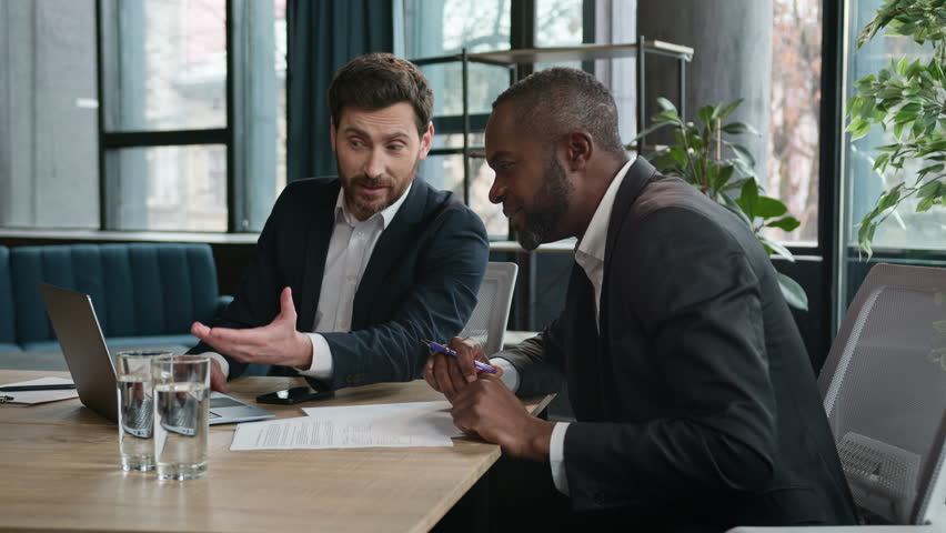 Happy excited two diverse businessmen multiethnic partners multiracial satisfied men enthusiastic partners at office meeting negotiate discuss good result business success with laptop computer data Royalty-Free Stock Footage #1105093477