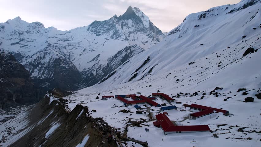 Aerial View Of Annapurna Base Camp On Snow Covered Mountain Side With Machapuchare Peak In Background. Dolly Forward 