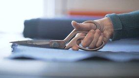 Hand holding big scissors and making cut of tissue. Probably it is tailor, designer, stylist or dressmaker making clothes in his or her studio. Close up shot. - Powered by Shutterstock - Get 15% off with code: PIKWIZARD15