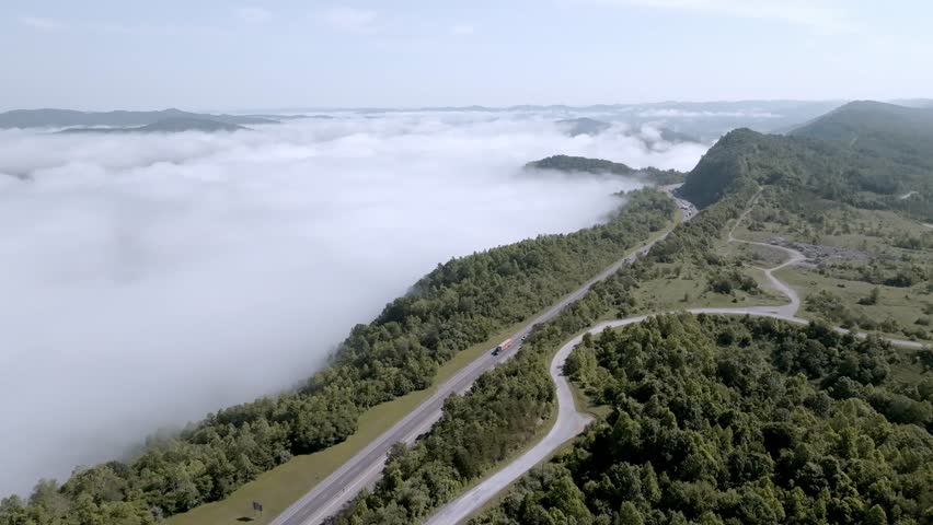 Clouds and fog along with traffic on Interstate 75 near Jellico, Tennessee in the Cumberland Mountains with drone video moving down.