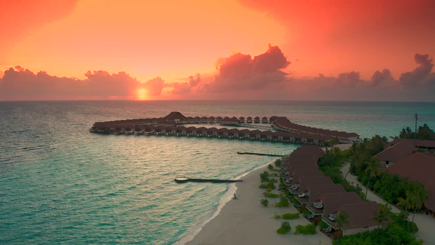 Maldives island sunset. Water bungalows resort at islands beach. Indian Ocean, Maldives. Beautiful sunset landscape, luxury resort and colorful sky. Artistic beach sunset under wonderful sky. Aerial Royalty-Free Stock Footage #1105107049