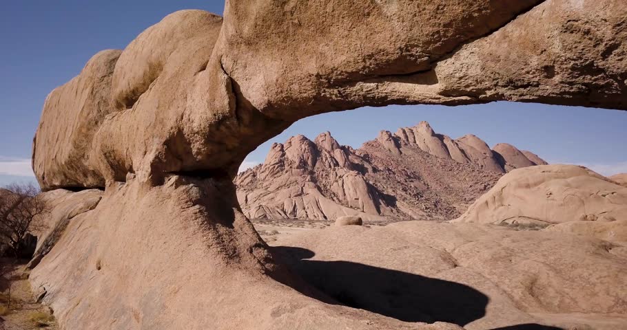 4K Aerial drone footage flying through a rock window in Spitzkoppe mountain in Namibia, Africa. African ancient rock formations, red rock landscape. Hiking. Cinematic High quality footage. Royalty-Free Stock Footage #1105109175