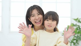 Asian woman and little girl talking to the camera. Video calling. Video chat.