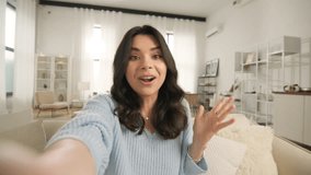Mobile cam view of happy latin american girl talking to camera holding phone recording vlog. Pretty smiley woman influencer social media streaming, video calling, chatting online using smartphone home