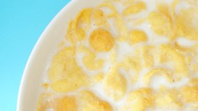 Top view of a bowl brimming with appetizing corn flakes bathed in creamy milk. Macro video captures the perfect breakfast, inviting you to savor the delightful combination of crunch and smoothness.
