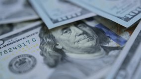 Hundreds of American dollars on table closeup. Camera slowly floats over pile of hundred dollar bills that lie on wooden table, with blurred background in close-up. Paper 100 dollar money cash. - Powered by Shutterstock - Get 15% off with code: PIKWIZARD15