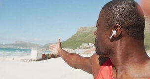 Animation of play screen over happy exercising african american man making video on sunny beach. Communication, technology, wellbeing, fitness and healthy lifestyle concept digitally generated video.