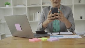 Businessman working in office at desk with financial graph document and laptop Freelance manager holding smartphone using chat messenger app. Career VIDEO 4k