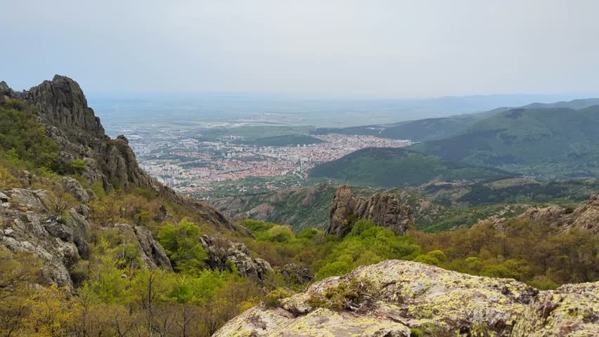 Panoramic view of the valley on top of the rocky ridge among the stones overlooking the beautiful valley. Outdoor and mountain hike background. Natural landscape in Bulgaria, Sliven