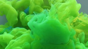 Green and blue paint splash each other in water against a grey background, colored ink spreads and bursts like a colorful cloud, fluorescent lighting and natural glitter. Slow motion, 4K. - Powered by Shutterstock - Get 15% off with code: PIKWIZARD15