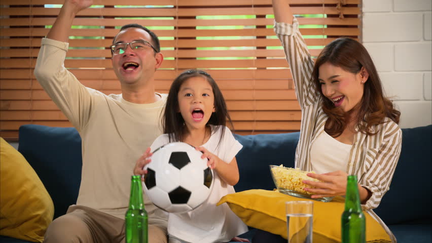 Happy family watching sports match together on television