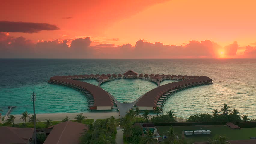 Maldives island sunset. Water bungalows resort at islands beach. Indian Ocean, Maldives. Beautiful sunset landscape, luxury resort and colorful sky. Artistic beach sunset under wonderful sky. Aerial | Shutterstock HD Video #1105129005