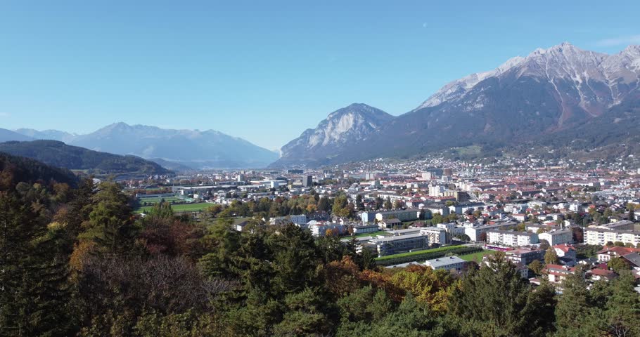 Aerial view of the city of Innsbruck from the hills of a forest on a sunny autumn day and a blue sky and in the background the alps with their peaks,Tyrol, Austria, Europe