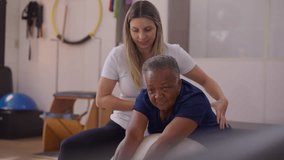 Female Physiotherapist Guiding African American Senior Woman in Pilates Ball Exercises, Old age mobility exercise routine - Powered by Shutterstock - Get 15% off with code: PIKWIZARD15