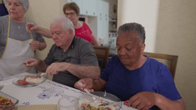 Group of diverse senior friends eating lunch together, elderly people reunion gathered for lunch. Close-up of a black older woman next to a caucasian male friend - Powered by Shutterstock - Get 15% off with code: PIKWIZARD15