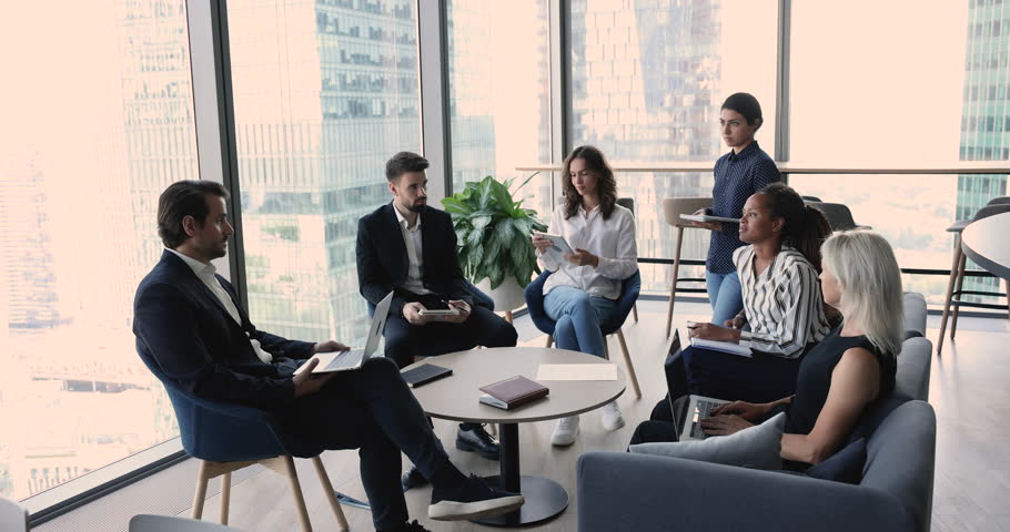 Diverse business team brainstorming on startup in office space. Multiethnic colleagues sitting in circle, talking, negotiating on project. Young African employee speaking, sharing ideas with group Royalty-Free Stock Footage #1105142403
