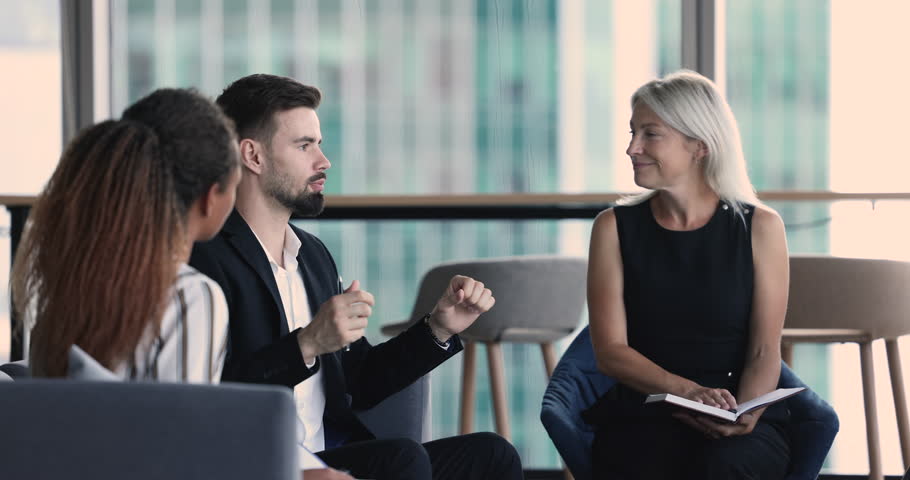 Serious young business professional guy speaking at team meeting, presenting creative idea for brainstorming, telling project plan, strategy, talking to diverse coworkers on office briefing Royalty-Free Stock Footage #1105142425