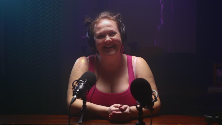 Podcast about body positivity. Chubby fat woman talks into a microphone about cooking delicious healthy food. Concept of diverse beauty and lifestyle. Slow motion, looks at the camera