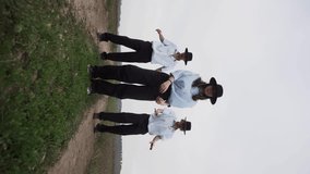A group of dancers in hats masterfully dance a dance on an abandoned road.Vertical video