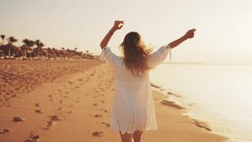 Carefree joyful woman tourist in airy white dress running along ocean sandy beach at sunset, rear view. Girl stretching arms in sides feeling freedom nature power on vacations. Travel tourism concept. - Powered by Shutterstock - Get 15% off with code: PIKWIZARD15