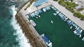 Aerial view of boats moored at Fuvahmulah Harbour, fishing port and famous dive site for tiger sharks, Fuvahmulah Island South Maldives. Nautical Vessel for marine tourism. 4K footage drone video