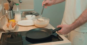 man cooking pancakes at weekend. The dough is poured into a frying pan close-up. Traditional food for Mardi Gras and Shrove Tuesday. Festive pancakes slow motion. close up cropped side view video