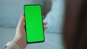 Women sittihg on couch using smartphone with chroma key green screen , scrolling through social media or online shop - internet, communications concept close up 4k template