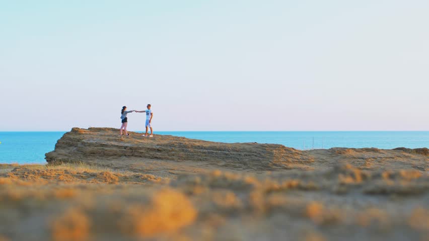 Happy couple walking on the top of the rock. With sea behind. Love and hapiness
