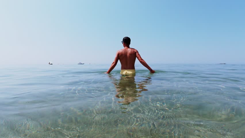 A man going into the sea. In slow motion. Shot from behing. Corfu, Greece. 