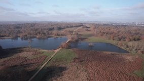 Aerial footage of Pen Pond in Richmond Park in autumn with city of London in the background.Richmond Park in the London Borough of Richmond upon Thames, is the largest of London's Royal Parks.