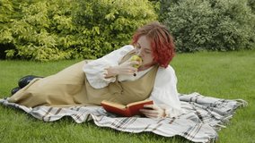 Gen Z girl wearing vintage outfit relaxing on lawn in backyard eating apple and reading book on summer day - Powered by Shutterstock - Get 15% off with code: PIKWIZARD15
