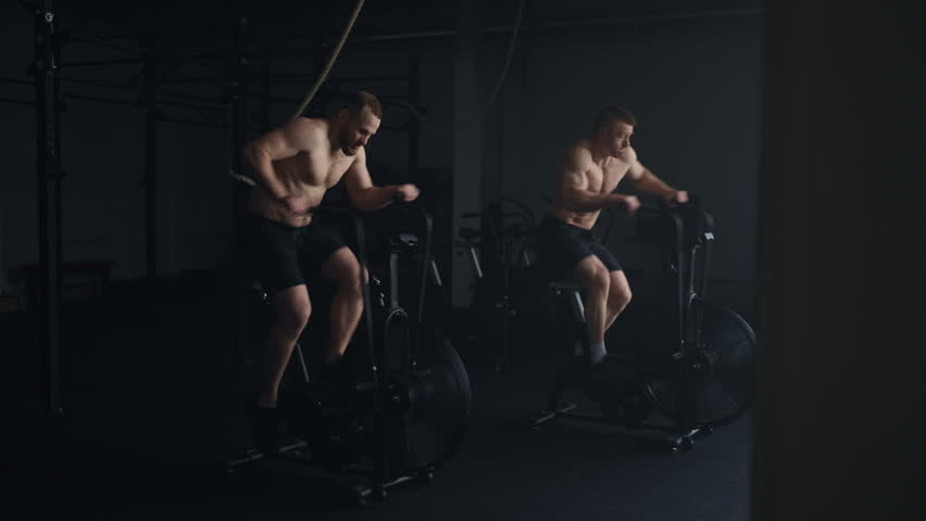 Hard Cardio Training On Stationary Bike In Gym, Two Athletic Men Rotating Pedals Royalty-Free Stock Footage #1105180059