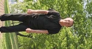Qigong wu qin xi, five animal games, rejuvenating exercises. Man practices yoga in city park. Vertical video