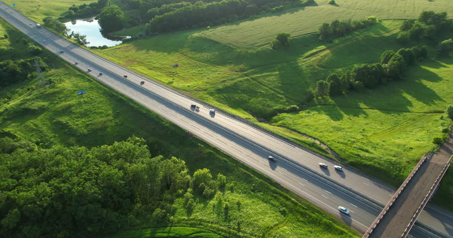 Aerial shot of traffic on the highway during sunset. Sunlight shines on the freeway. Multi-lane traffic. Drone view