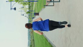 Sportive female jogging in city park along pedestrian path. Vertical video. Athletic woman in sportswear running outdoors, maintaining healthy lifestyle. Sport activity. Fitness workout exercises