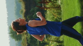 Sportive athletic woman running in green city park in evening. Vertical video. Fit muscular female athlete jogging outdoors, doing intense cardio workout training. Sportswoman doing fitness activity
