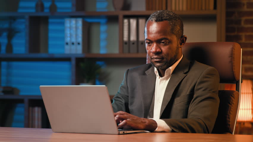 Concentrated african american businessman typing on laptop pensive thoughtful man thinking deep in thought ponder looking for solution inspired come up with idea eureka raise index finger up remember Royalty-Free Stock Footage #1105195283