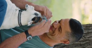 Love and communication with pets as a way to mental health. Vertical video of a middle-aged man with his Jack Russell Terrier dog. Close-up view. Slow motion 4k footage.
