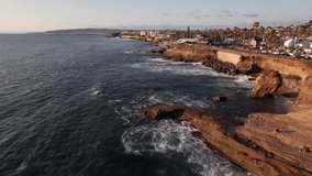 Beautiful sunset cliffs public nature park near San Diego in southern California during sunset golden hour from an above drone and aerial view moving over rocks, Pacific Ocean waves, and car traffic