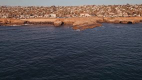 Beautiful sunset cliffs public nature park near San Diego in southern California during sunset golden hour from an above drone and aerial view moving over rocks, Pacific Ocean waves, and car traffic