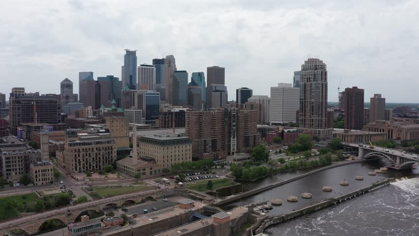 Wide reverse pullback aerial shot of downtown Minneapolis, Minnesota along the Mississippi River. 4K Royalty-Free Stock Footage #1105202607