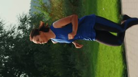 Woman running in park at evening golden sunset lights. Vertical video. Sportive athletic female in sportswear jogging outdoors in evening dusk. Fitness cardio activity. Intense workout training