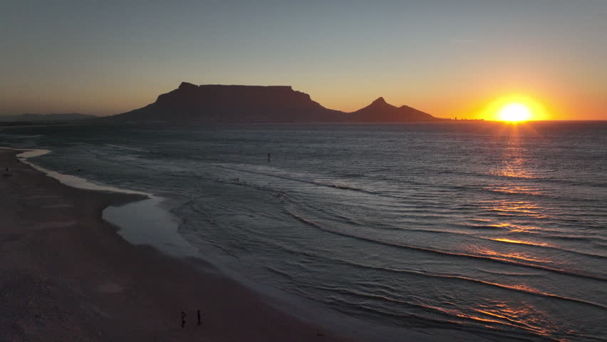 Cape Town South Africa family people walking on sand windy surf wave Table Mountain drone aerial cinematic Lions Head sunset beach stunning mountain and ocean landscape orange gold sun backward motion